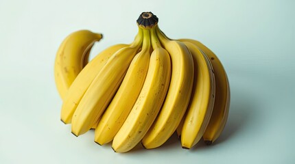 A bunch of yellow bananas clustered together on a light blue background in a close up still life