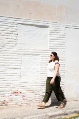 Tourist walking along white wall in sunny day