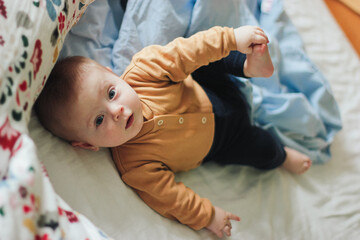 Cute Baby in Cozy Jacket Lying on Bed with Blue Blanket