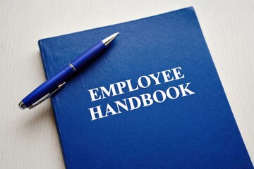 Employee handbook placed on a wooden surface with a blue pen nearby, symbolizing workplace guidance and policies