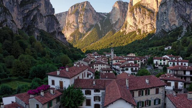 Sunlight warming traditional stone houses of la hermida village, nestled between dramatic mountain peaks of picos de europa national park, surrounded by verdant landscape