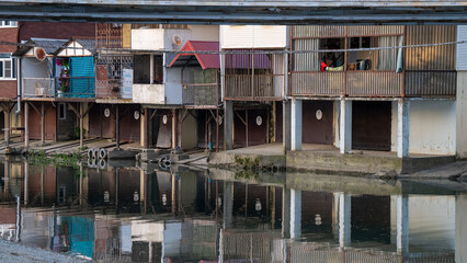 Riverside Stilt Houses with Reflections on Calm Water in a Rustic Settlement