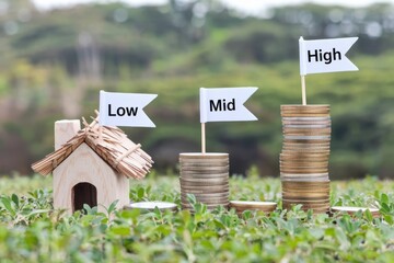 Property value appreciation trend concept. Miniature house and coin stacks illustrate financial levels: low, mid, and high.