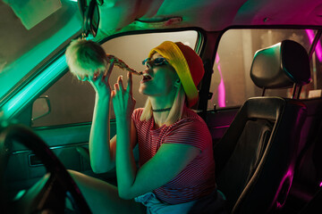 Retro fashioned woman eating pizza in car.