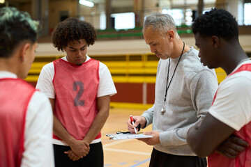 Coach explaining strategy to basketball players during timeout