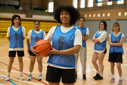 Female basketball player holding ball with teammates in background