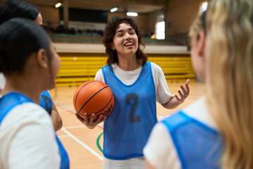 Female basketball player talking to teammates during training in gym