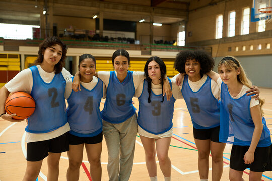 Female basketball team smiling and embracing on court