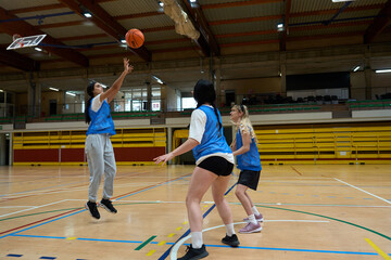 Female basketball players competing in indoor court game