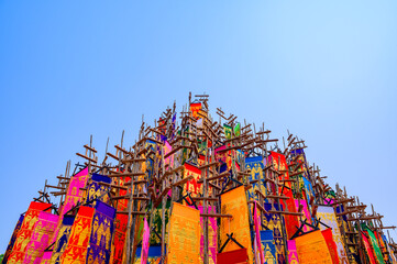 A vibrant display of traditional Lanna flags (Tung) in various colors, rising against a clear blue sky, part of a cultural festival in Northern Thailand.