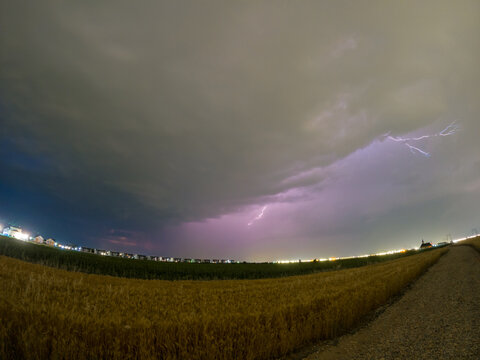 Evening landscape with a strong summer thunderstorm with electrical discharges. Dramatic phenomenon of nature with lightning falling from the sky on the wheat field - Powered by Adobe