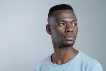Obraz premium Man in Casual Attire Poses Thoughtfully Against a Light Backdrop