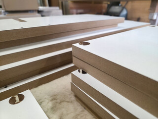 Detailed view of neatly stacked wooden panels prepared for assembly in a workshop environment during daylight hours