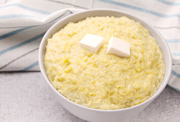 Vegetarian breakfast: millet porridge with butter in a white plate on a gray background