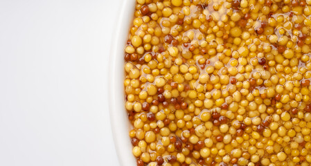French Dijon mustard in a metal spoon, top view on mustard grains background. Gastronomy concept,...