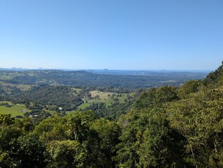 Fototapeta premium Wide-angle view of rolling hills, forests, and farmland under a clear blue sky. A peaceful hinterland scene showcasing the natural beauty of the Australian countryside.