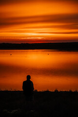 Bright orange sunset on the lake with silhouettes of swans and ducks