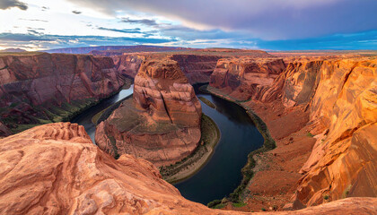 The breathtaking view captures a dramatic horseshoe-shaped bend in a deep canyon carved by the Colorado River, surrounded by layered red rock formations at sunset.