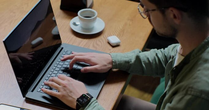 Overhead view of a handsom man in casualwear sitting at cafe table with coffee cup and working on laptop. Business lifestyle concept.