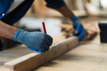 Close up of hands carpenter man using pencil for mark on timber during working in carpenter wood...