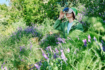 Woman using virtual reality glasses in a blooming meadow during spring