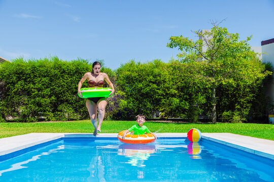 Mother and son having fun diving into a pool on a sunny day in Argentina