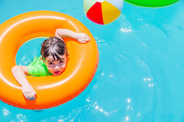 Boy playing in a pool with an orange float on a sunny day in Argentina