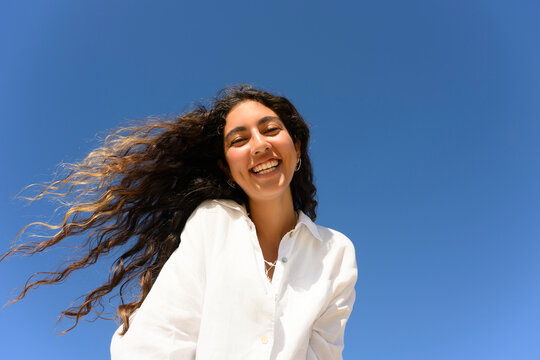 Smiling woman with long curly hair enjoying a sunny day outdoors