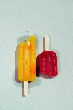 Close-up of mango and strawberry popsicles on a sunny day