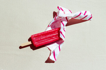 Red popsicle partially unwrapped on a sunny day