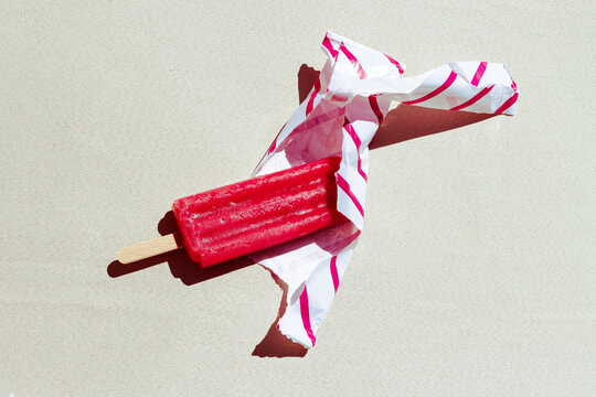 Red popsicle partially unwrapped on a sunny day