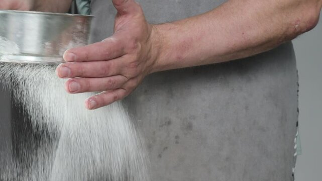 Man holding metal sifter with flour ready for sifting in kitchen