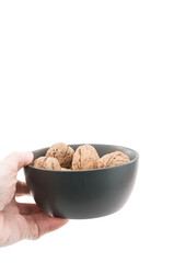 mano che regge una ciotola in ceramica scura con frutta secca, noci, isolato su bianco o trasparente