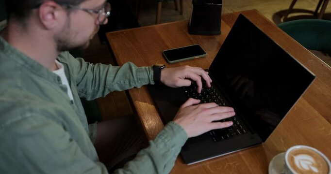 Overhead view of a handsom man in casualwear sitting at cafe table with coffee cup and working on laptop. Business lifestyle concept.