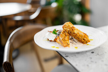 Close-up of a gourmet fish dish with mustard seeds, creamy sauce, and herbs, elegantly plated on a white plate in a restaurant setting. Blurred background enhances the fine dining atmosphere