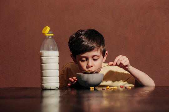 Boy eating breakfast cereal with milk using a spoon