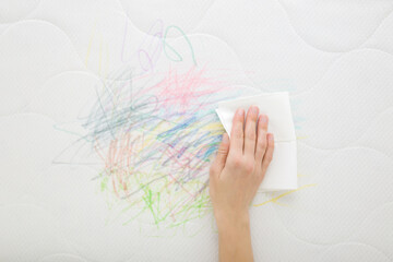 Woman hand holding dry soft paper napkin and cleaning scratches lines of colorful markers from...