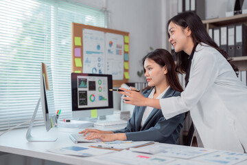 Two asian businesswomen are discussing and analyzing financial charts and graphs showing company...