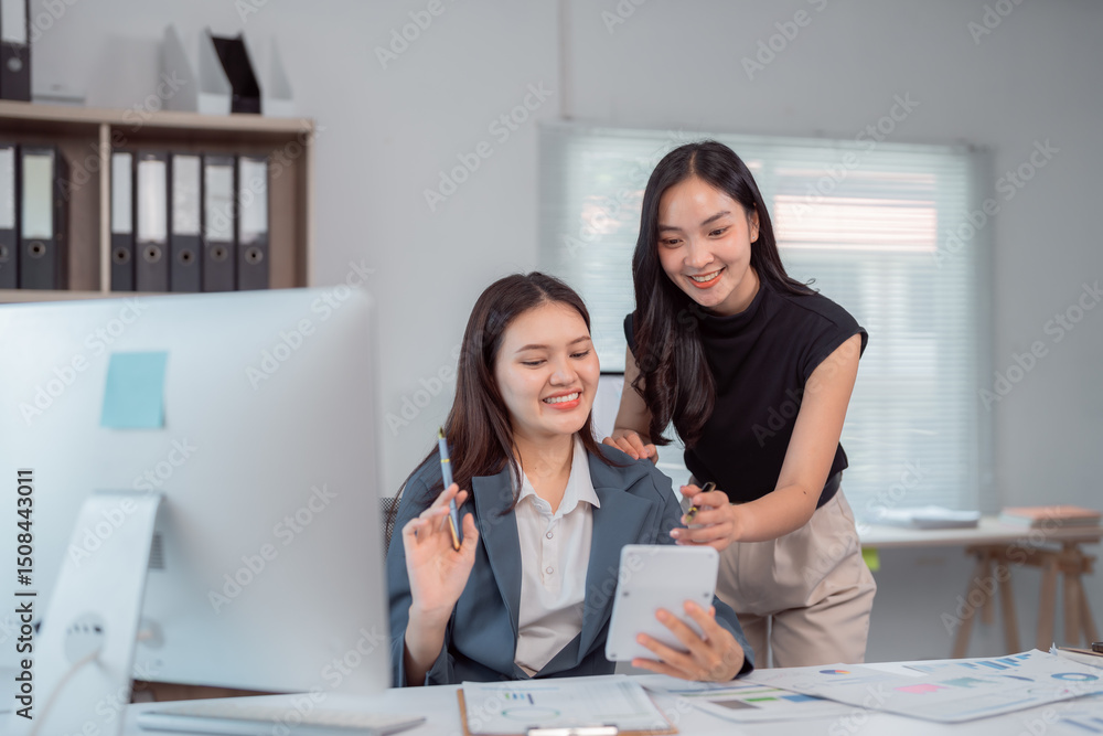 Poster two happy asian businesswomen discussing, brainstorming, collaborating on project using tablet and a