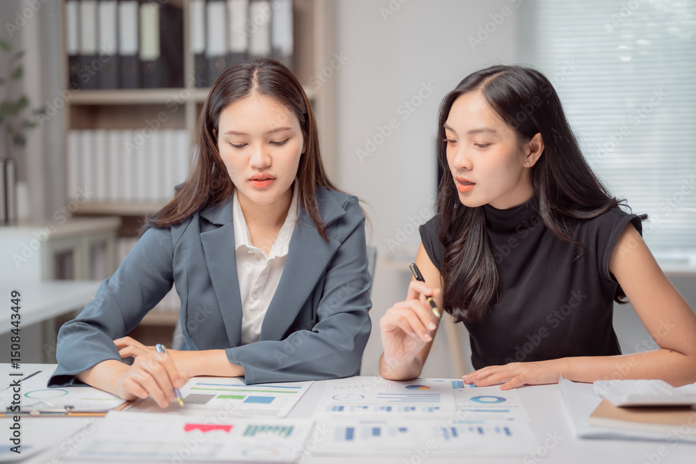 Aufkleber two young businesswomen are discussing financial data and analyzing charts and graphs while working 