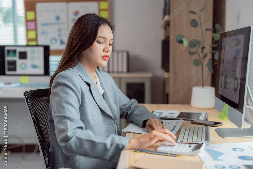 Poster young businesswoman calculating and analyzing financial data using calculator and computer while wor