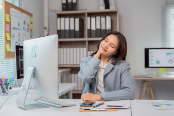 Asian businesswoman experiencing neck and shoulder pain from prolonged computer use in the office,...