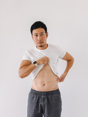 Asian male showing six-pack abs with confident expression