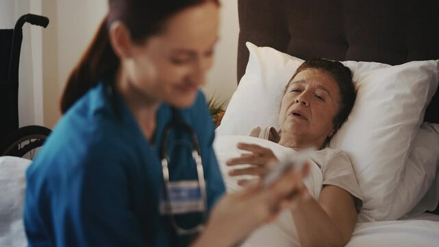 Rude nurse ignoring senior woman with disability and playing on phone, neglect