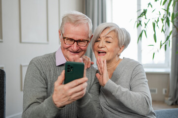 Video call. Happy senior couple woman man with smartphone having video call. Mature old grandmother grandfather talking speaking online. Older generation modern tech usage. Virtual meeting online chat