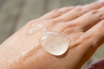 Fototapeta premium Close-Up View of Transparent Gel Droplet on Hand Skin Giving a Fresh and Hydrated Appearance in Natural Light Conditions