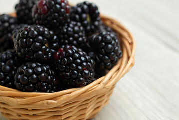 Fresh and Juicy Blackberries in a Woven Basket on a Light Wooden Surface, Perfect for Healthy Eating and Delicious Recipes