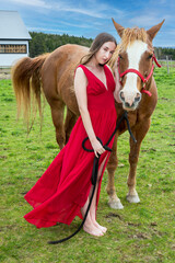A young woman in a red dress with a horse