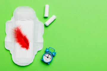 Ringing alarm clock with sanitary female tampons and menstrual sanitary pads. Medical concept of...