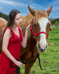 A young woman in a red dress with a horse